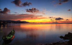 Lit Powerboat In Bay At Sunset Wallpaper
